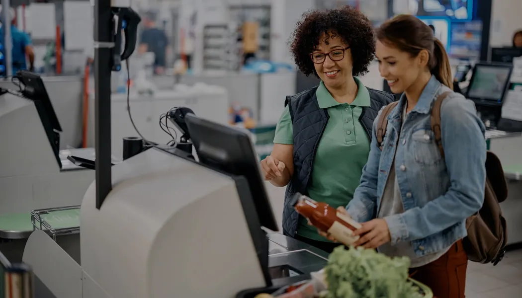 Empregada do mercado ajudando o Cliente no caixa de auto atendimento no mercado.