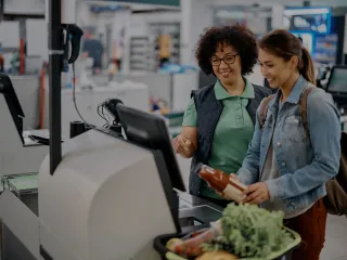Empregada do mercado ajudando o Cliente no caixa de auto atendimento no mercado.