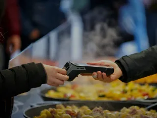 Pessoa usando cartão contactless em uma máquina de cobrança em um mercado.